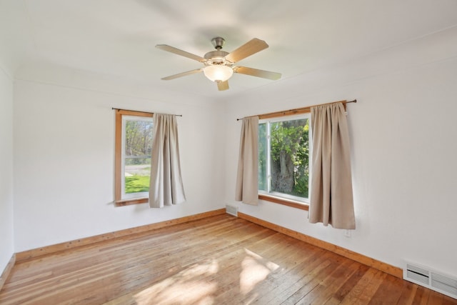 empty room with plenty of natural light, hardwood / wood-style flooring, baseboards, and a ceiling fan