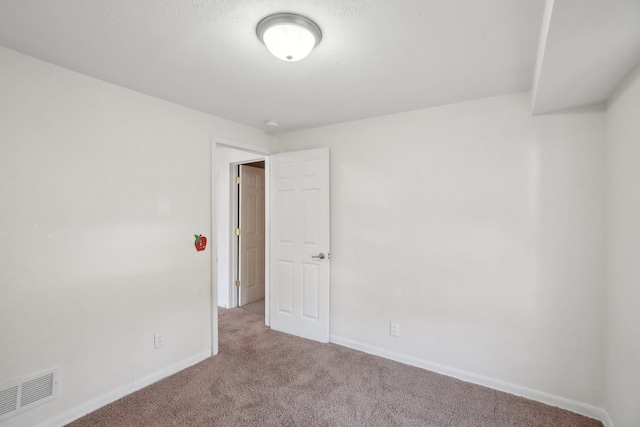 empty room featuring carpet and baseboards