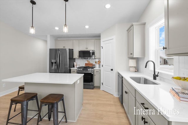 3772 Ambrosia Dr SW Unit 25, Grand Rapids, MI 49534 - kitchen featuring appliances with stainless steel finishes, a sink, gray cabinets, a kitchen bar, and light wood-style floors