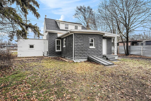 rear view of property featuring roof with shingles and fence