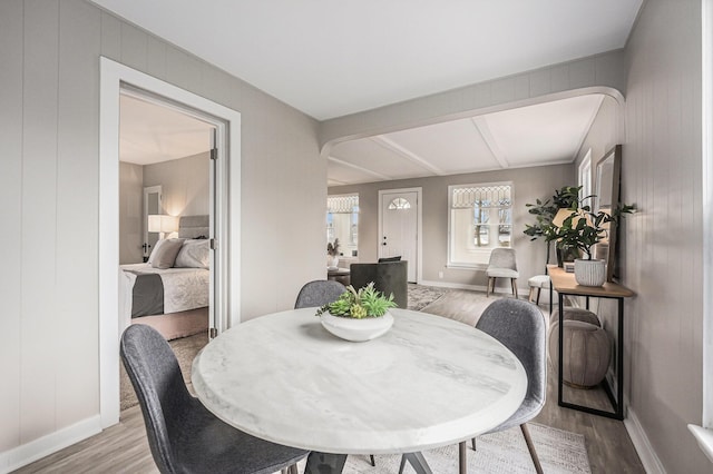 dining room featuring light wood-style floors, baseboards, and arched walkways