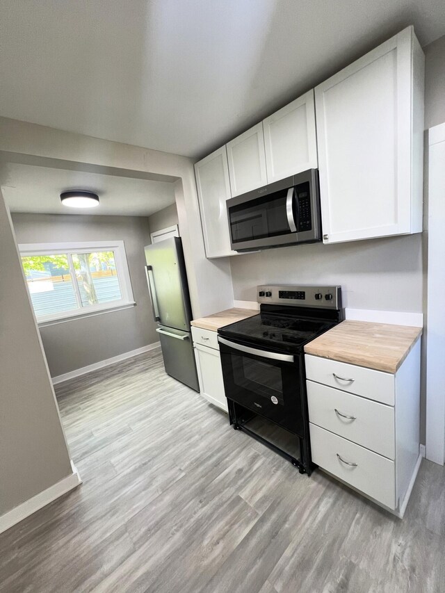 kitchen featuring stainless steel appliances, wood counters, and light wood-style floors