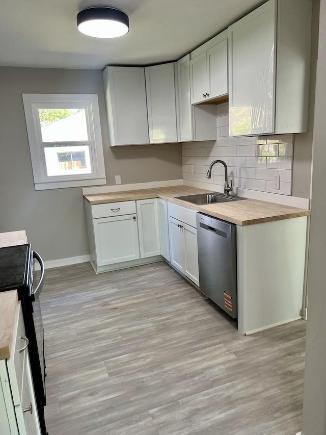 kitchen with stainless steel dishwasher, a sink, butcher block counters, tasteful backsplash, and baseboards