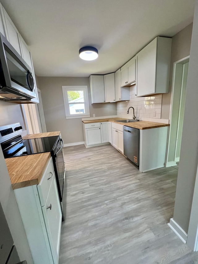 109 S Lake Ave, Spring Lake, MI 49456 - kitchen featuring stainless steel appliances, wood counters, a sink, baseboards, and decorative backsplash