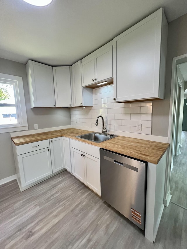109 S Lake Ave, Spring Lake, MI 49456 - kitchen with stainless steel dishwasher, butcher block countertops, a sink, light wood finished floors, and white cabinetry