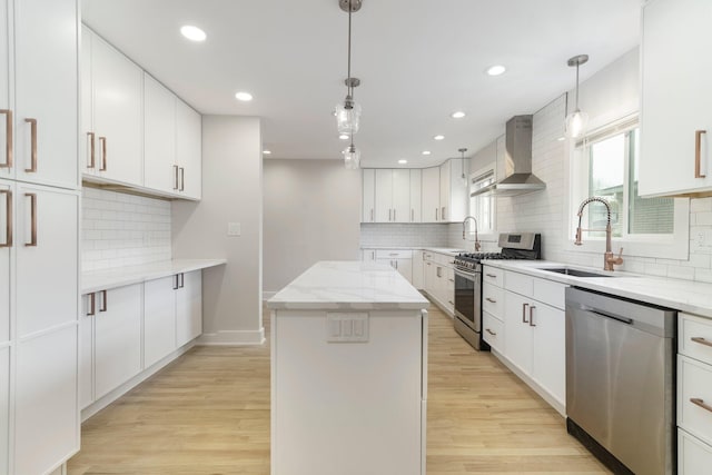 25720 Southwood Dr, Southfield, MI 48075 - kitchen featuring wall chimney range hood, stainless steel appliances, a sink, a kitchen island, and light wood finished floors