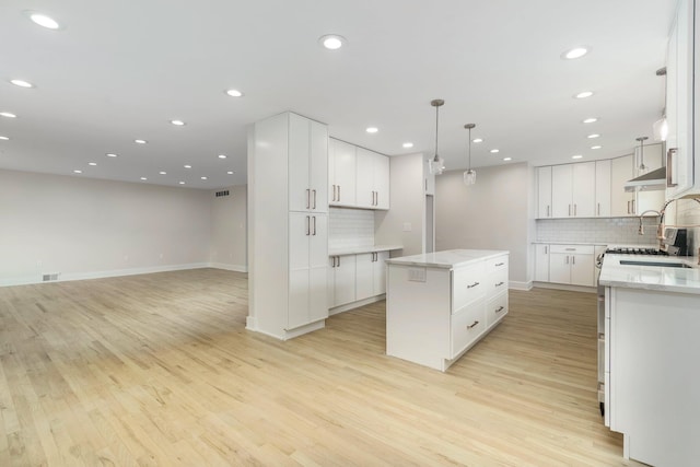 25720 Southwood Dr, Southfield, MI 48075 - kitchen featuring a kitchen island, backsplash, light wood-type flooring, white cabinets, and recessed lighting
