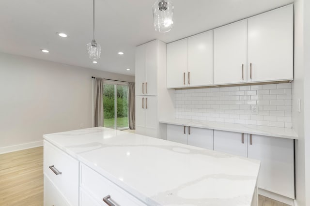 25720 Southwood Dr, Southfield, MI 48075 - kitchen with light wood finished floors, hanging light fixtures, white cabinets, light stone countertops, and recessed lighting