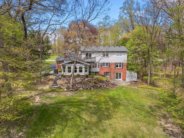 5445 Washakie Trl, Brighton, MI 48116 - rear view of house featuring a lawn, stairs, and brick siding