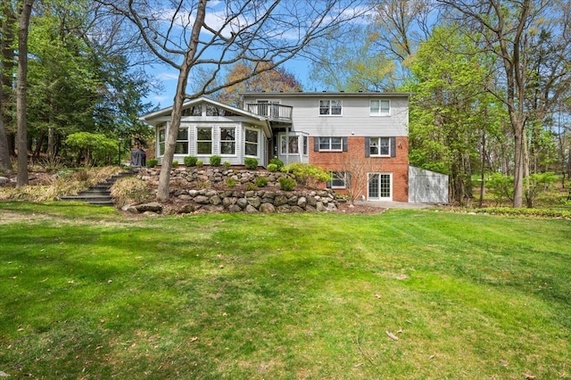 5445 Washakie Trl, Brighton, MI 48116 - back of house featuring a balcony, brick siding, a yard, and stairway
