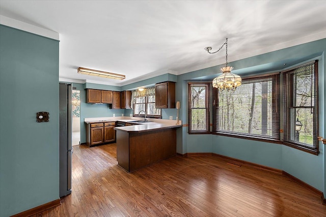 5445 Washakie Trl, Brighton, MI 48116 - kitchen with a sink, a peninsula, a chandelier, and baseboards