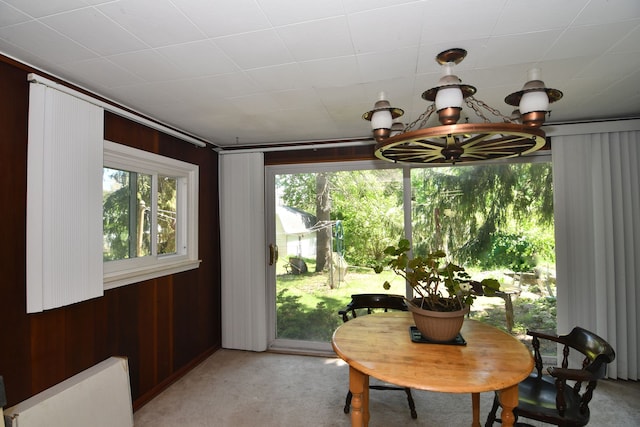 1209 Applewood Dr, White Lake, MI 48386 - dining area with a chandelier, light carpet, wood walls, and radiator heating unit