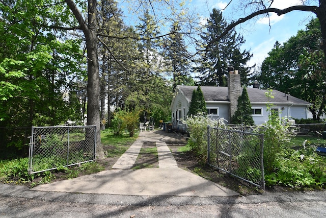 1209 Applewood Dr, White Lake, MI 48386 - view of home's exterior featuring a gate, a chimney, fence, and driveway
