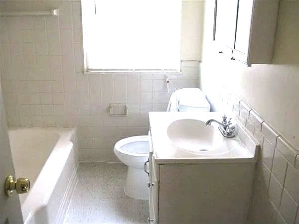 13892 Eastburn St, Detroit, MI 48205 - bathroom with toilet, tile walls, vanity, a tub, and a shower