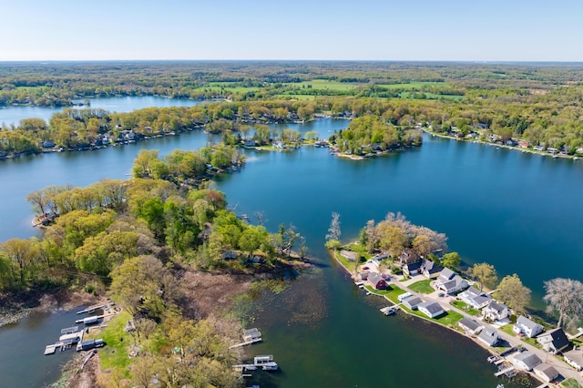 aerial view of property and surrounding area featuring a forest and a nearby body of water
