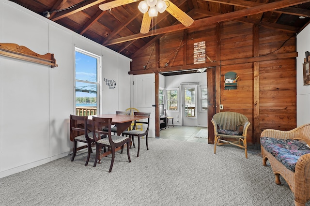 dining room featuring wooden ceiling, high vaulted ceiling, beamed ceiling, ceiling fan, and wood walls