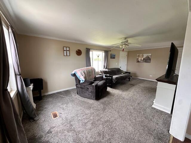 1120 W Montgomery Rd, Camden, MI 49232 - carpeted living room with ornamental molding, ceiling fan, and baseboards