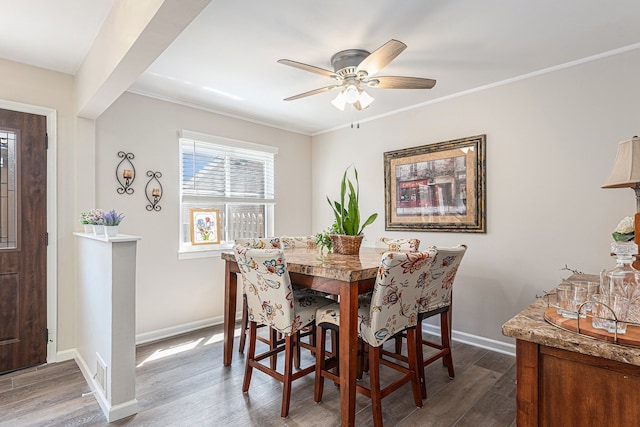 dining area with wood finished floors, a ceiling fan, baseboards, and ornamental molding
