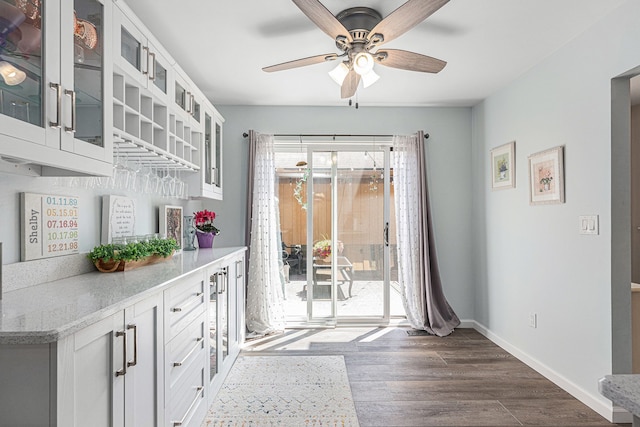 dining space with ceiling fan, dark wood-style flooring, and baseboards