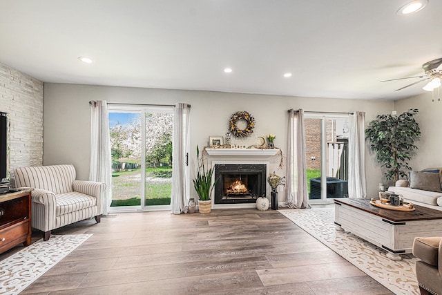 living room with ceiling fan, a lit fireplace, hardwood / wood-style floors, and recessed lighting