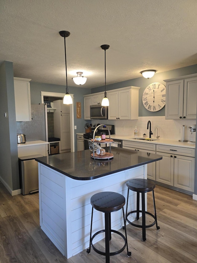 567 Angler Ave, Coldwater, MI 49036 - kitchen with a sink, gas range oven, stainless steel microwave, wood finished floors, and a kitchen breakfast bar