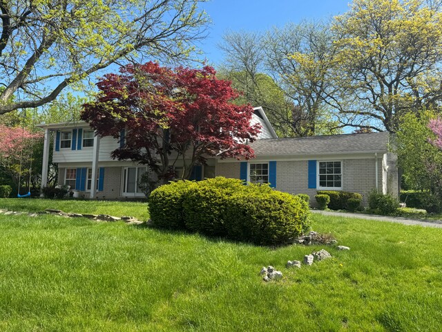 view of front facade with brick siding and a front lawn