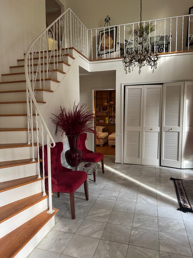 entrance foyer with stairway, a chandelier, a high ceiling, and marble look tile flooring