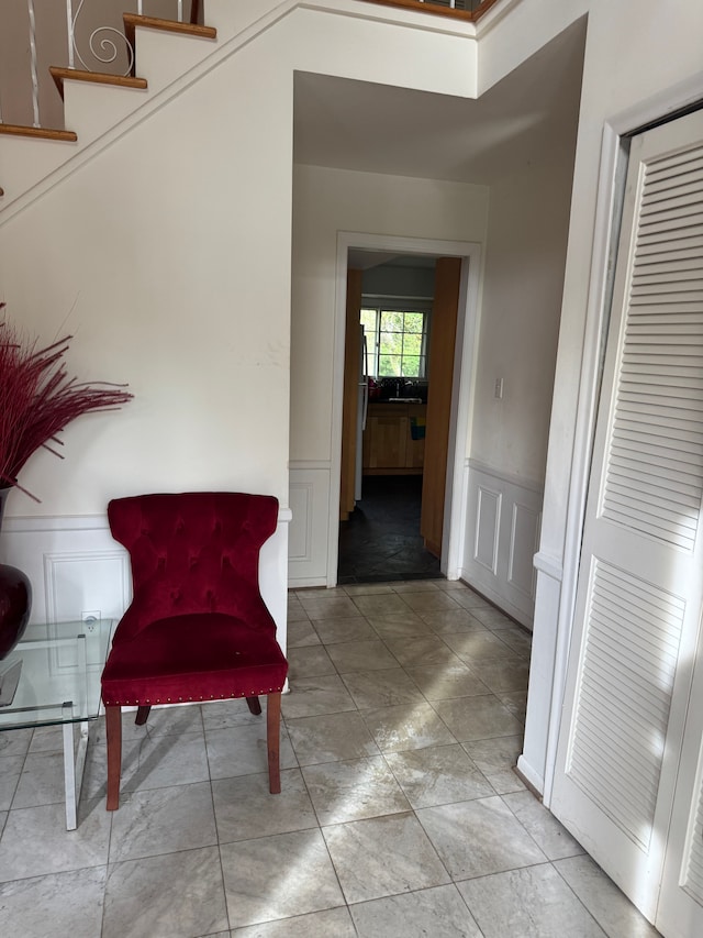 sitting room with a decorative wall and a wainscoted wall