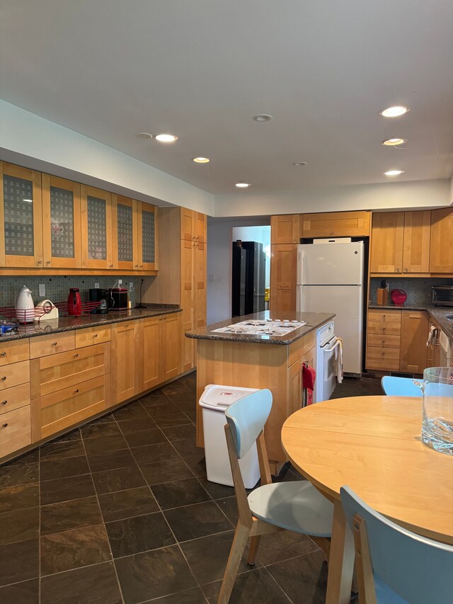 kitchen with white appliances, a kitchen island, glass insert cabinets, backsplash, and recessed lighting