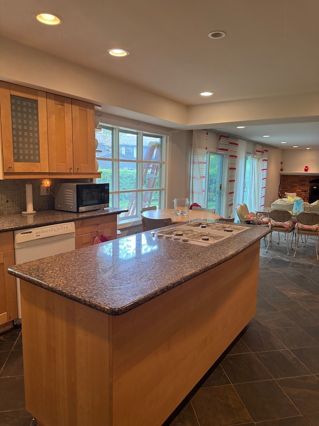 kitchen with white appliances, a center island, recessed lighting, dark stone counters, and open floor plan