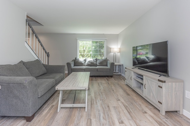 living room with light wood finished floors, stairs, and baseboards
