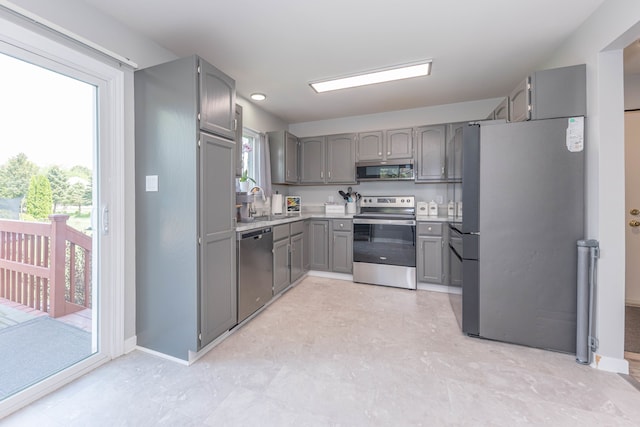 kitchen featuring stainless steel appliances, gray cabinets, light flooring, light countertops, and baseboards