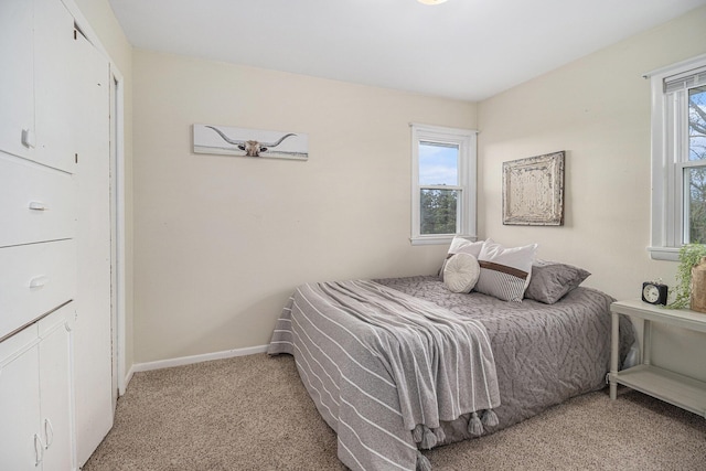 bedroom featuring light colored carpet, multiple windows, and baseboards