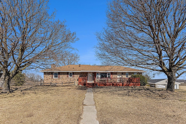 ranch-style house with a chimney, a deck, and brick siding