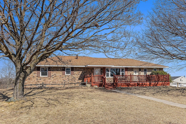 ranch-style house featuring brick siding and a deck