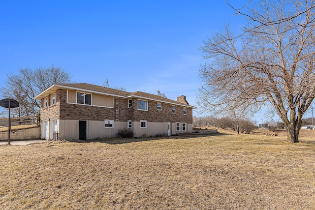 back of house featuring a chimney, a garage, and brick siding