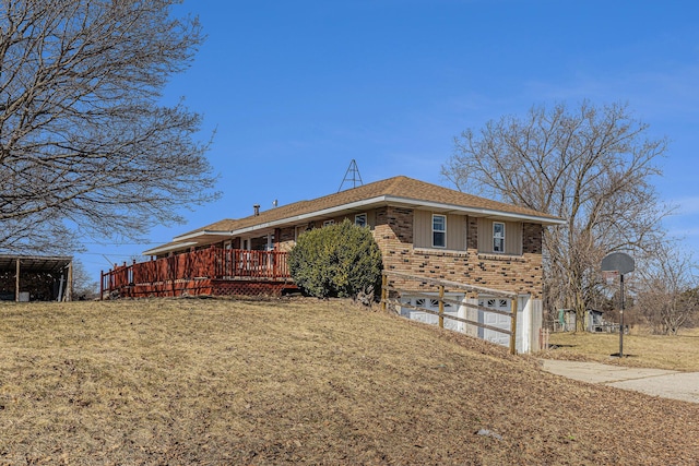 view of side of home featuring concrete driveway, a deck, a yard, board and batten siding, and brick siding