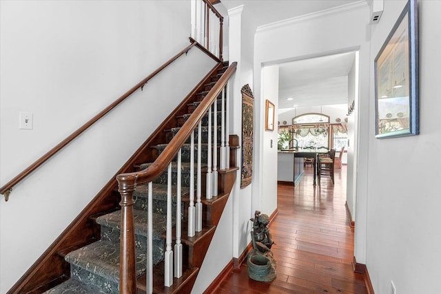 stairway featuring hardwood / wood-style floors, ornamental molding, and baseboards