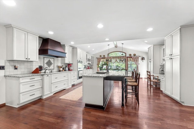 kitchen with premium range hood, lofted ceiling, dark wood finished floors, and white cabinets