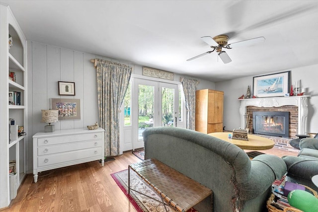 living room featuring a ceiling fan, a brick fireplace, and wood finished floors