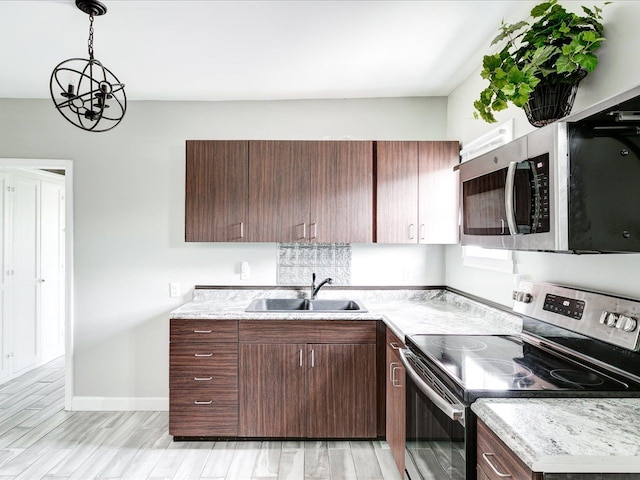 kitchen with appliances with stainless steel finishes, a sink, light countertops, and light wood-style floors