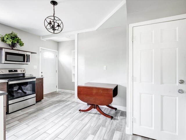 kitchen featuring appliances with stainless steel finishes, baseboards, light wood-style floors, a chandelier, and pendant lighting