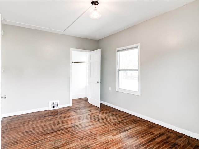 unfurnished bedroom with baseboards, wood finished floors, a closet, and attic access