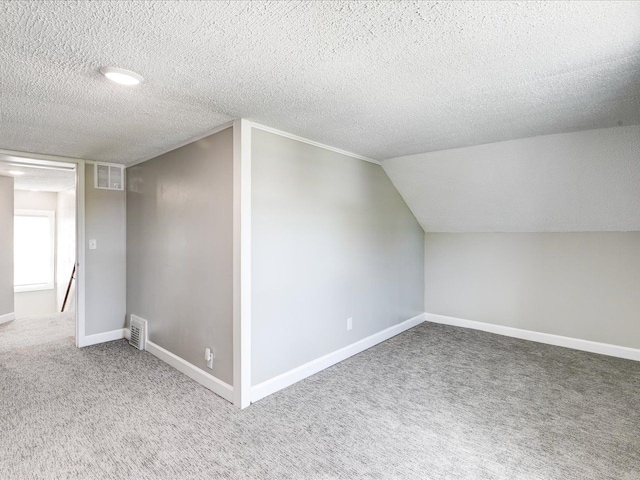 bonus room with carpet, a textured ceiling, baseboards, and vaulted ceiling