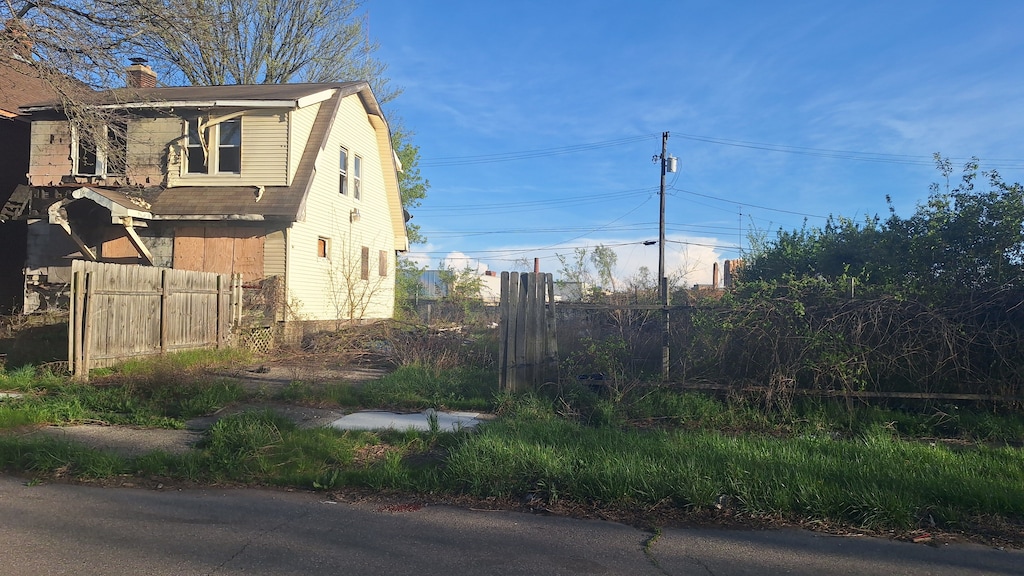 view of home's exterior featuring a gambrel roof, fence, and a chimney