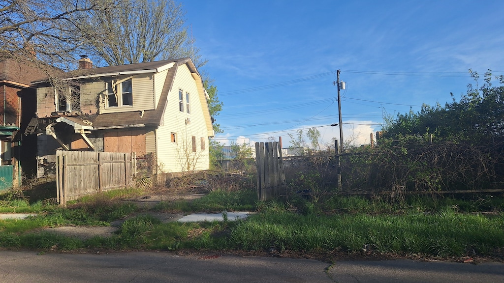view of side of property featuring a gambrel roof, a chimney, and fence