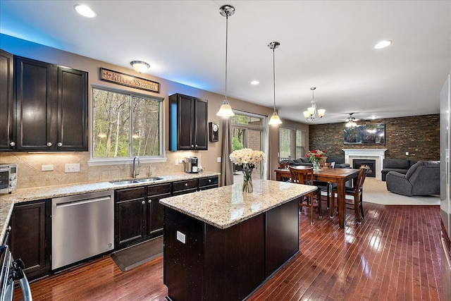 5633 Golf Pointe Dr, Clarkston, MI 48348 - kitchen featuring dishwasher, a sink, a center island, a fireplace, and light stone counters