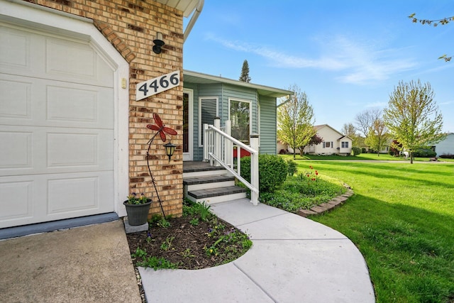 entrance to property with a yard, a garage, and brick siding