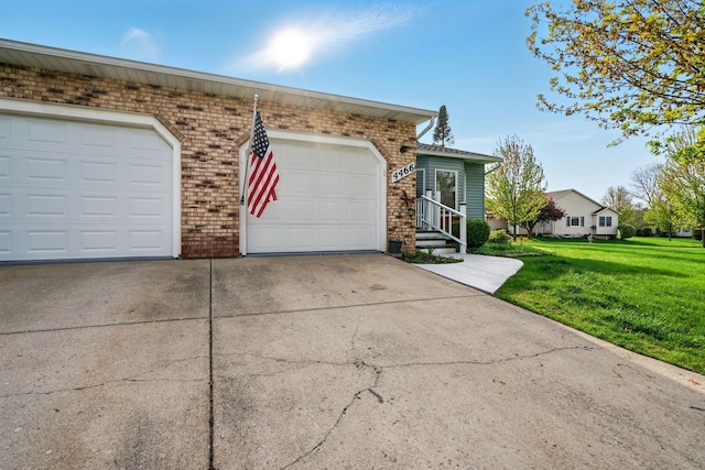 view of front of house featuring brick siding, a front yard, and driveway