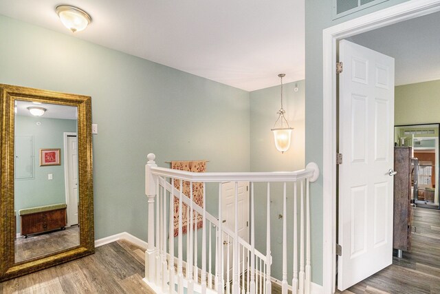hall featuring an upstairs landing, wood finished floors, and baseboards